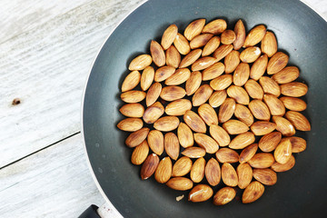 Roasted salted almond nuts in a pan, top view of a healthy vegetarian food
