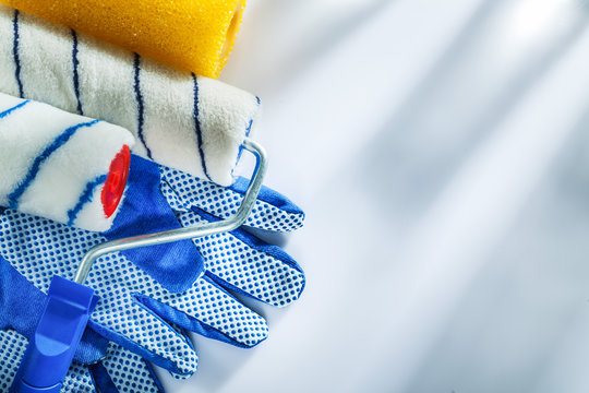 Pair of protective gloves paint rollers on white background