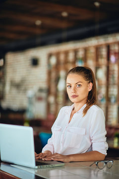 Businesswoman sitting in restaurant and usig laptop. Hands on keyboard.