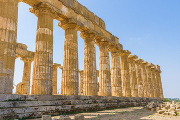 Obraz premium Ruins of the doric Temple of Hera (Temple E) inside the archaeological park of Selinunte, an ancient Greek city on a seaside hill in the south west coast of Sicily.