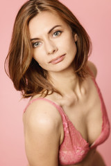 Naklejka premium Beautiful woman in lace underwear smiling, pink background