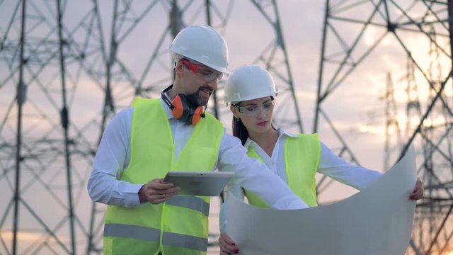 Working professional engineers stand near power lines, close up.