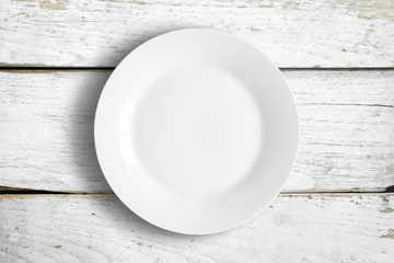 Top view of empty white food dish on a wooden background.