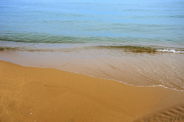 Wet sand on the beach. A part of the sea is visible.