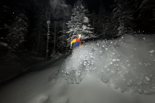 freerider snowboarder jumping at night with a springboard in the forest