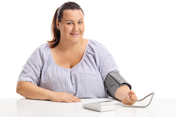 Overweight woman measuring her blood pressure and looking at the camera