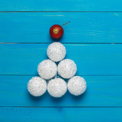abstract christmas idea, white decorative balls lined in the form of a Christmas tree on blue boards, the upper red ball symbolizes a star, the concept of a holiday