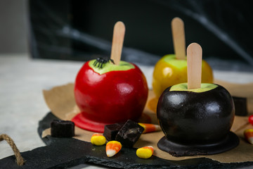 Obraz na płótnie Canvas Halloween style sweets - black poisoned, red and orange caramel apples, rustic background