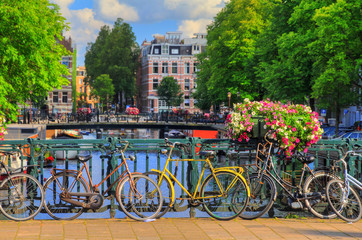 Fototapeta premium Piękne, żywe letnie kwiaty i rowery na moście nad słynnymi kanałami światowego dziedzictwa w Amsterdamie w Holandii