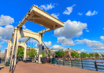Beautiful close up wide angle of the skinny bridge (magere brug) over the river Amstel in Amsterdam, the Netherlands, on a sunny summer day with blue sky and some clouds
