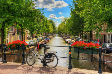 Beautiful vibrant summer flowers and a bicycle on a bridge on the famous world heritage canals of Amsterdam, The Netherlands 