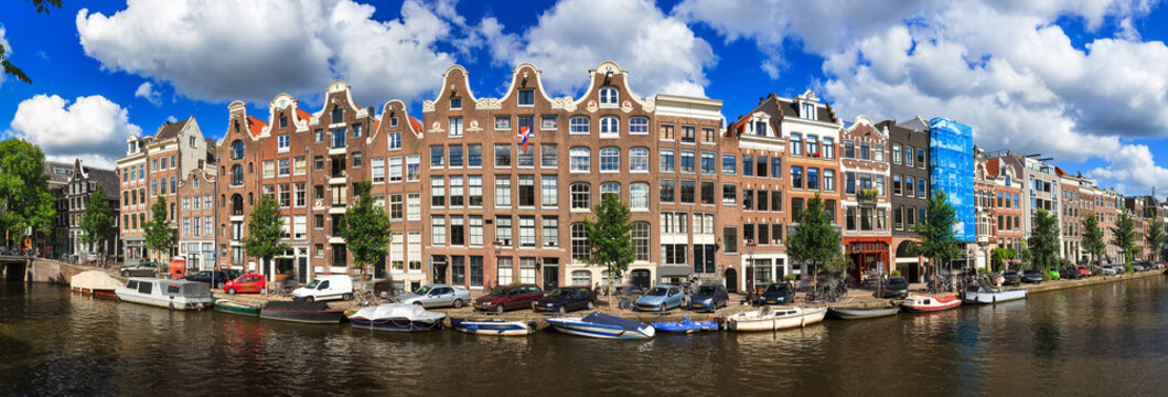 Beautiful panoramic linear panorama of the UNESCO world heritage Prinsengracht canal in Amsterdam, the Netherlands, on a sunny summer day with a blue sky and clouds
