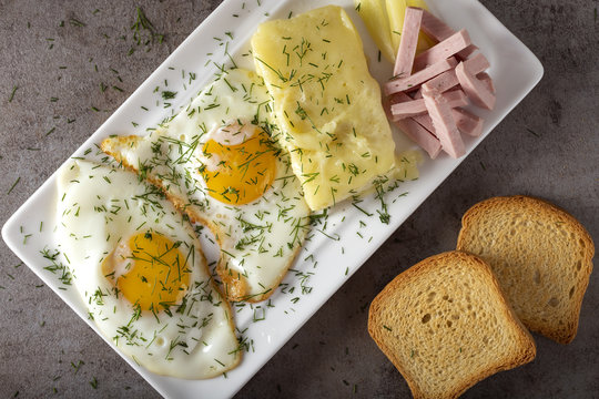Fried eggs with melted Romanian cheese called cas and some parizer