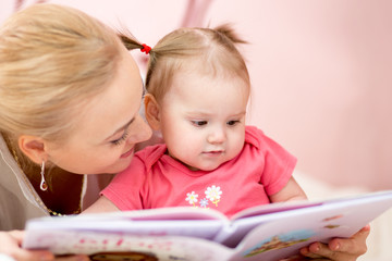 happy mother read book to baby girl at home