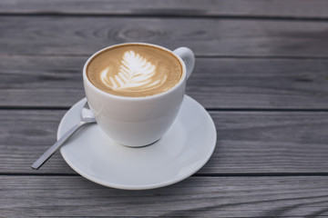a cup of black coffee on a saucer with a small spoon close-up