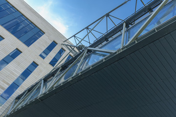 fragment of a suspension bridge over a canal connecting a buildings on a blue sky background