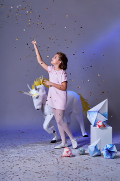 Holidays, christmas, new year, x-mas,concept. Little girl in elegance dress for party pointing finger on glitter confetti. Fashion lady teenage poses full-length in studio, gray purple background.