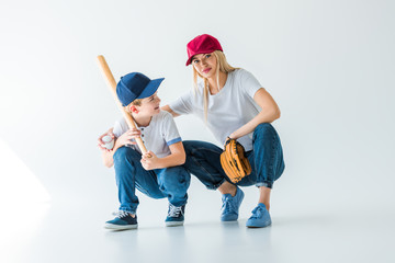 mommy and son squatting with baseball bat and glove on white