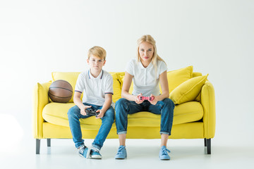 serious mother and son playing video game, basketball ball on yellow sofa