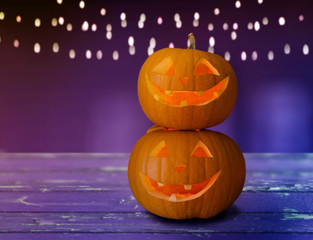 holidays, halloween and decoration concept - close up of carved pumpkins on table over ultra violet...
