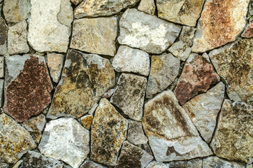 Color background of raw natural stone, for the facade of the house in gray and brown shades
