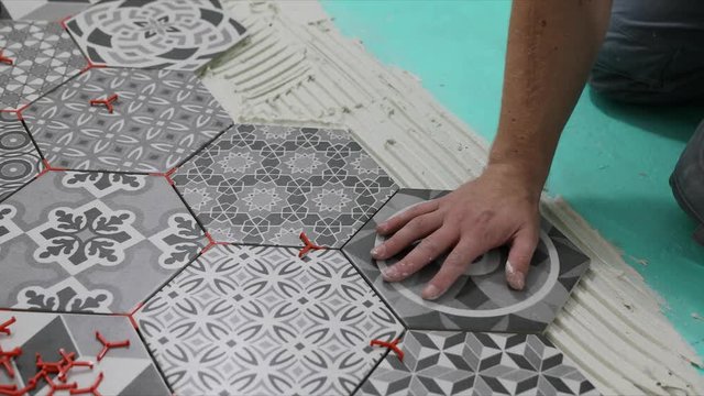 man laying hexagon floor tiles