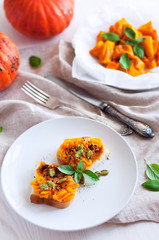 Toast with mashed pumpkin with green, pepper and seeds. Sliced roasted pumpkin on white parchment sprinkled with spices. Angle view still life on wooden and fabric background.