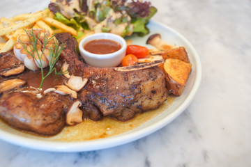 T-Bone steak with fresh vegetable salad and French fries.
