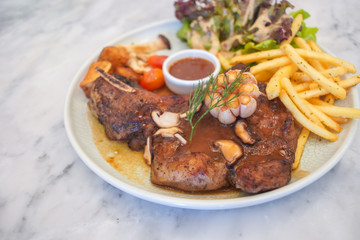 T-Bone steak with fresh vegetable salad and French fries.