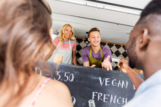 street sale, payment and people concept - happy customers giving credit card at food truck seller