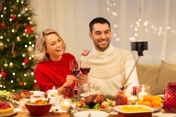 christmas, holidays, technology and people concept - happy couple in taking selfie by smartphone at home dinner