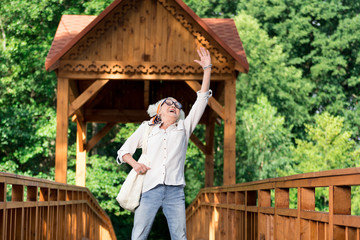 Jumping high. Emotional expressive senior woman putting one hand up and jumping while feeling excited