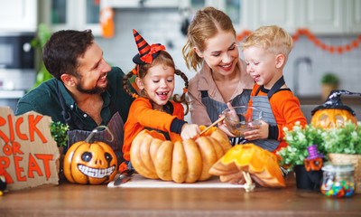 happy Halloween! family mother father and children cut pumpkin for holiday home.