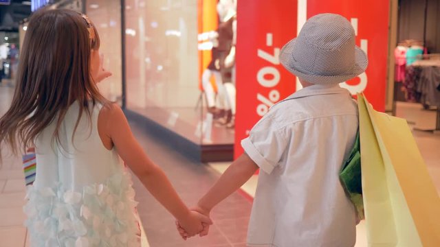 big discounts, Fashionable children go past shop windows with dummies after purchases on expensive boutiques in shopping mall