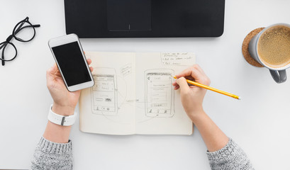 app design, technology and business concept - web designer or developer with smartphone working on...