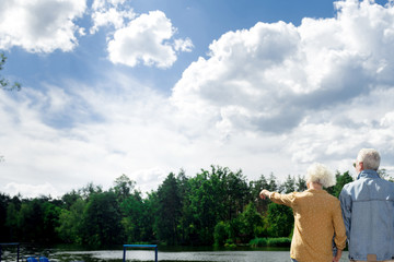 Showing trees. Aged couple enjoying beautiful nature and looking at the trees in front of them