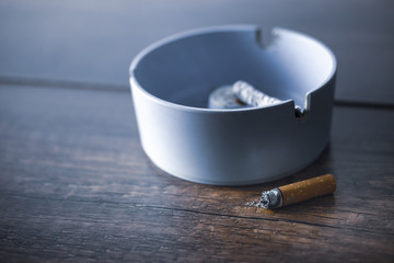 ashtray with cigarette on wood table.
