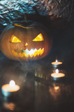 Pumpkin lantern with the scary face smiling with candles on a dark background