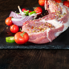 Raw meat, salt, pepper, tomato, spices, garlic, rustic wood background