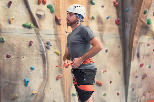 Man climber preparing to climb artificial indoor climbing wall