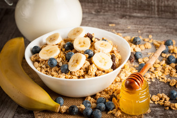 Healthy breakfast concept with oat flakes and fresh berries on rustic background. Food made of granola and muesli. Healthy banana smoothie with blackberries, honey and milk.