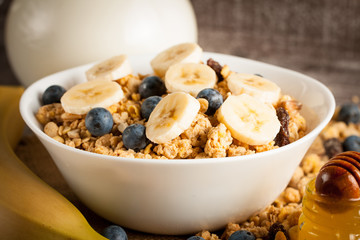 Healthy breakfast concept with oat flakes and fresh berries on rustic background. Food made of granola and muesli. Healthy banana smoothie with blackberries, honey and milk.