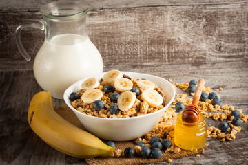 Healthy breakfast concept with oat flakes and fresh berries on rustic background. Food made of granola and muesli. Healthy banana smoothie with blackberries, honey and milk.