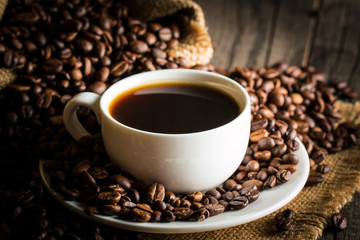 Coffee cup and beans on a rustic background. Coffee Espresso and a piece of cake with a curl. Cup of Coffee and coffee beans on table.