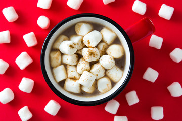 Christmas cocoa with marshmallow in mug on red background. Top view