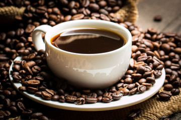 Coffee cup and beans on a rustic background. Coffee Espresso and a piece of cake with a curl. Cup of Coffee and coffee beans on table.