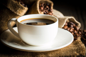 Coffee cup and beans on a rustic background. Coffee Espresso and a piece of cake with a curl. Cup of Coffee and coffee beans on table.