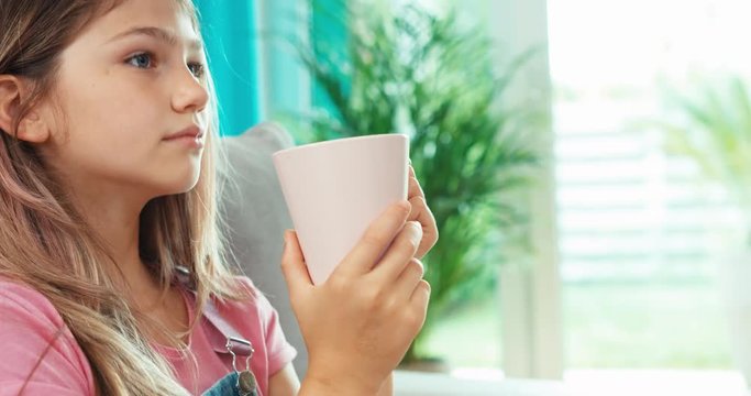 Portrait preteen girl drinking tea and smiling at camera