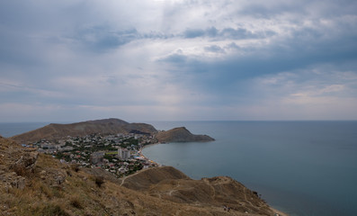 Fototapeta na wymiar Cape Black sea in the village of Ordzhonikidze in the Crimea, in the summer with a textured sky with clouds and hilly terrain, landscape