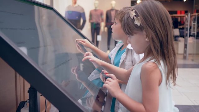 modern childhood, nice kids uses interactive touchscreen display For search best route at shopping center